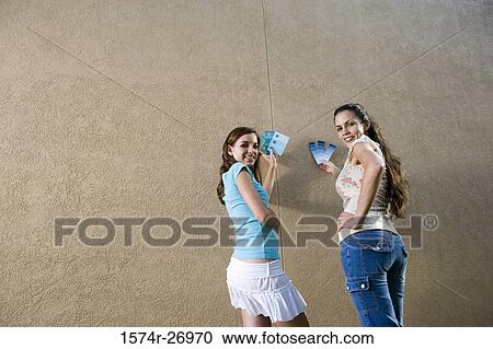 Portrait of sisters holding color swatches against wall View Large Photo Image Stock Image - Portrait of sisters holding color swatches against wall. Fotosearch
