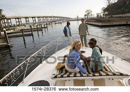 Stock Photograph - Portrait of smiling friends relaxing on the deck of a boat. Fotosearch