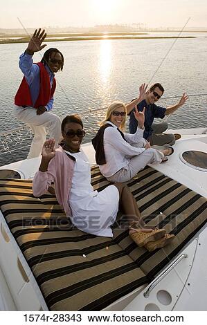 Portrait of smiling friends relaxing and waving on the deck of a boat View Large Photo Image Stock Image - Portrait of smiling friends relaxing and waving on the deck of a boat. Fotosearch