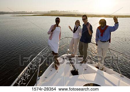 Picture - Portrait of smiling friends waving on the deck of a boat. Fotosearch