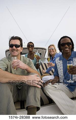 Portrait of smiling friends with glass of champagne on the deck of a boat View Large Photo Image Stock Photo - Portrait of smiling friends with glass of champagne on the deck of a boat. Fotosearch