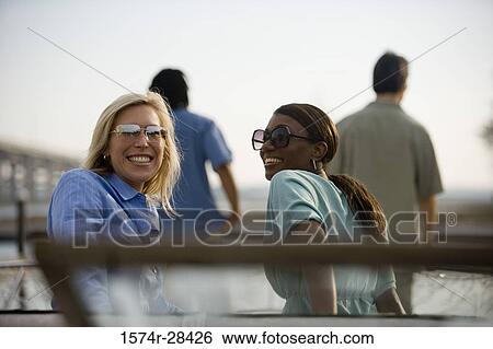 Portrait of smiling mid adult women wearing sunglasses View Large Photo Image Stock Photograph - Portrait of smiling mid adult women wearing sunglasses. Fotosearch