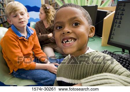 Portrait of smiling schoolboys and a girl sitting with computers in the library View Large Photo Image Stock Image - Portrait of smiling schoolboys and a girl sitting with computers in the library. Fotosearch