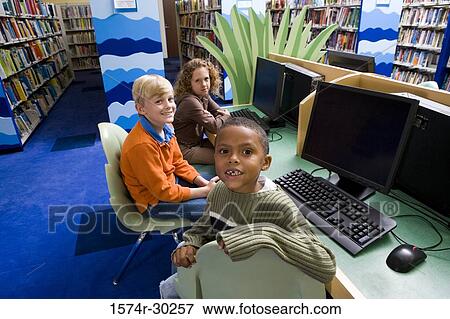 Portrait of smiling schoolboys and a girl sitting with computers in the library View Large Photo Image Stock Photo - Portrait of smiling schoolboys and a girl sitting with computers in the library. Fotosearch