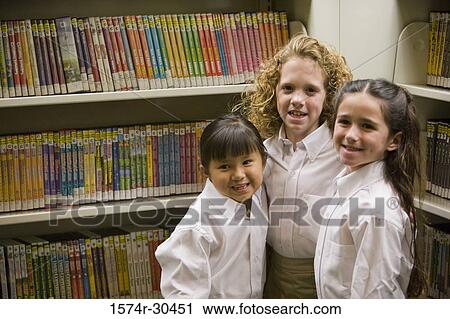 Portrait of smiling schoolgirls standing by shelf in the library View Large Photo Image Stock Image - Portrait of smiling schoolgirls standing by shelf in the library. Fotosearch