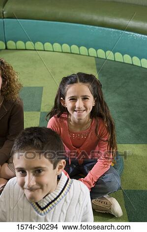 Picture - Portrait of smiling students sitting on floor in the library. Fotosearch