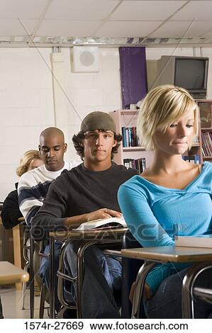 Portrait of student wearing cap while other students reading book in the classroom View Large Photo Image Stock Photo - Portrait of student wearing cap while other students reading book in the classroom. Fotosearch