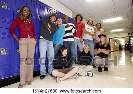 Stock Image - Portrait of students with female teacher smiling and standing by lockers. Fotosearch