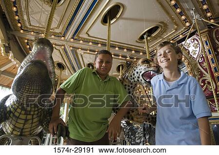 Stock Image - Portrait of teenage boys standing in a carousel by a carousel leopard. Fotosearch