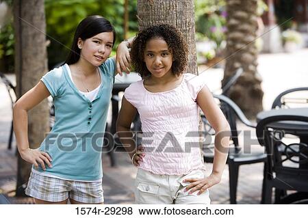 Stock Photo - Portrait of teenage girls leaning on a tree trunk. Fotosearch