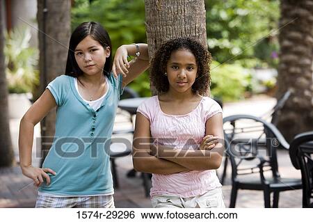 Stock Photograph - Portrait of teenage girls leaning on a tree trunk. Fotosearch