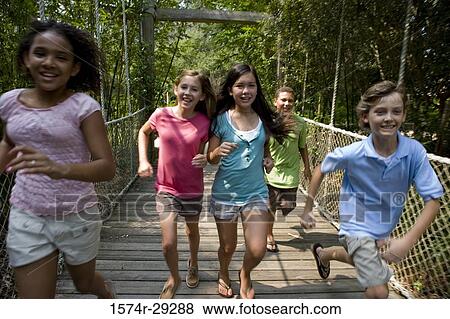 Portrait of teenagers running on a rope bridge with trees in the background View Large Photo Image Stock Photo - Portrait of teenagers running on a rope bridge with trees in the background. Fotosearch