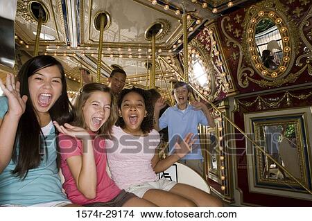 Picture - Portrait of teenagers sitting in a carousel and shouting. Fotosearch