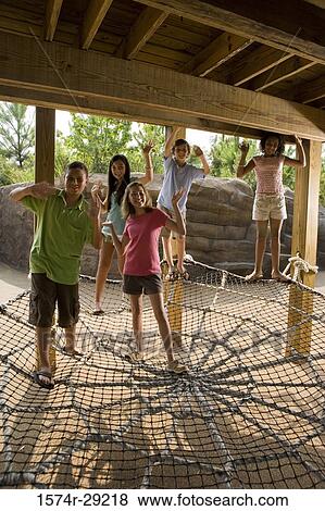 Portrait of teenagers standing on a net tied to the wooden columns and waving hands View Large Photo Image Stock Photo - Portrait of teenagers standing on a net tied to the wooden columns and waving hands. Fotosearch