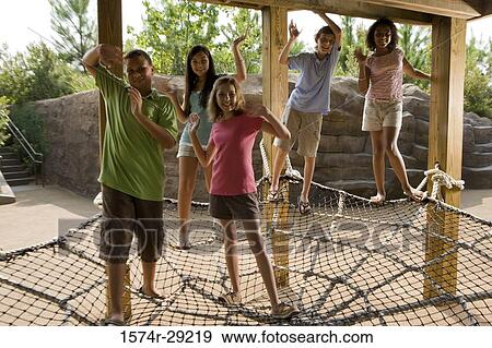 Portrait of teenagers standing on a net tied to the wooden columns and waving hands View Large Photo Image Stock Photo - Portrait of teenagers standing on a net tied to the wooden columns and waving hands. Fotosearch