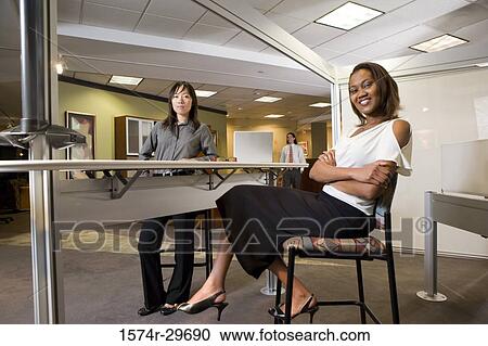 Portrait of two cheerful businesswoman sitting in the office View Large Photo Image Stock Image - Portrait of two cheerful businesswoman sitting in the office. Fotosearch