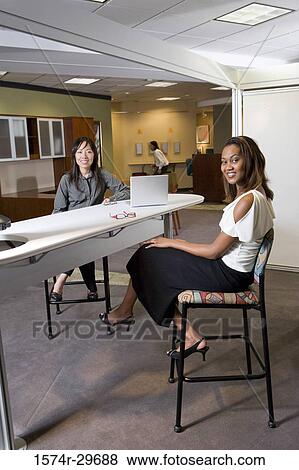 Portrait of two cheerful businesswoman sitting in the office View Large Photo Image Stock Photo - Portrait of two cheerful businesswoman sitting in the office. Fotosearch