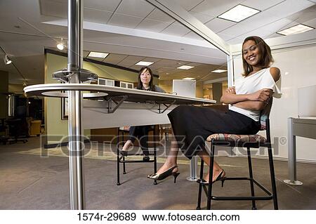 Portrait of two cheerful businesswoman sitting in the office View Large Photo Image Stock Photo - Portrait of two cheerful businesswoman sitting in the office. Fotosearch