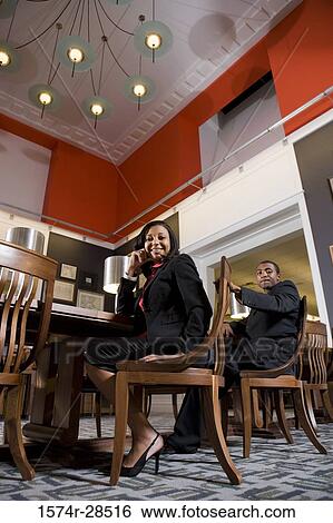 Stock Photograph - Portrait of well-dressed businesspeople sitting on chairs in an office. Fotosearch