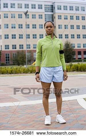 Portrait of young woman in sports clothing standing on walkway with building in the background View Large Photo Image Stock Image - Portrait of young woman in sports clothing standing on walkway with building in the background. Fotosearch