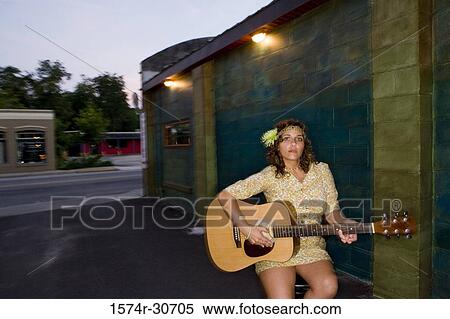 Stock Photography - Portrait of young woman sitting with guitar. Fotosearch
