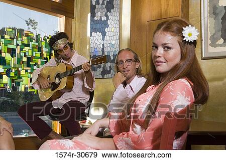 Stock Photo - Portrait of young woman smiling while father and brother sitting behind. Fotosearch