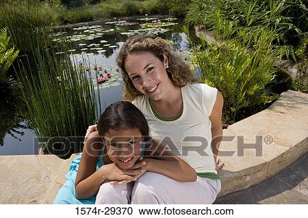 Portrait of young woman with her daughter sitting by pond View Large Photo Image Stock Image - Portrait of young woman with her daughter sitting by pond. Fotosearch