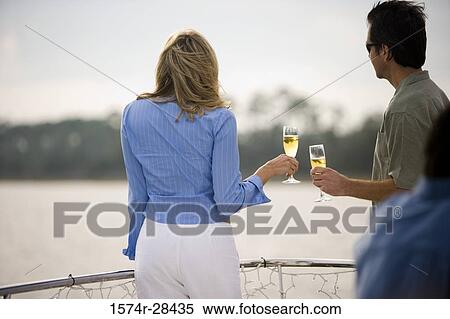 Rear view of a mid adult couple standing with glass of champagne View Large Photo Image Stock Photography - Rear view of a mid adult couple standing with glass of champagne. Fotosearch