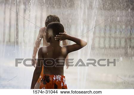 Rear view of a shirtless boy playing in water View Large Photo Image Picture - Rear view of a shirtless boy playing in water. Fotosearch