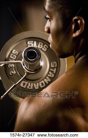 Rear view of shirtless young man working out with dumbbell View Large Photo Image Stock Photo - Rear view of shirtless young man working out with dumbbell. Fotosearch