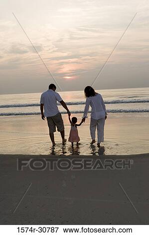 Rear view of young couple with daughter on the beach at sunset View Large Photo Image Stock Photo - Rear view of young couple with daughter on the beach at sunset. Fotosearch