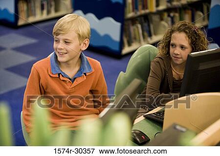 Schoolboy and girl sitting by computers in the library View Large Photo Image Stock Photo - Schoolboy and girl sitting by computers in the library. Fotosearch