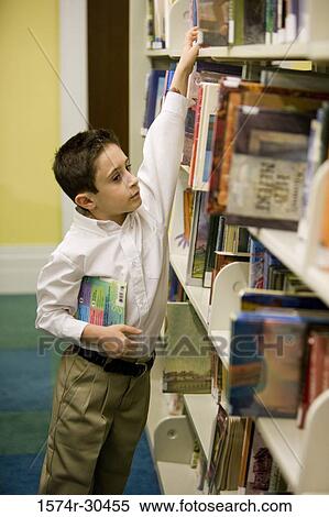 Schoolboy removing a book from shelf in the library View Large Photo Image Stock Photography - Schoolboy removing a book from shelf in the library. Fotosearch
