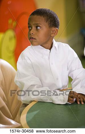 Schoolboy sitting by table and looking away View Large Photo Image Stock Photo - Schoolboy sitting by table and looking away. Fotosearch
