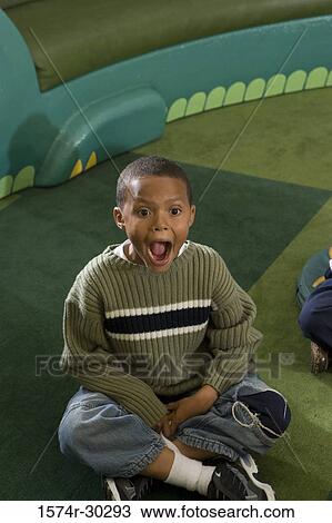 Schoolboy sitting on floor with mouth open View Large Photo Image Stock Image - Schoolboy sitting on floor with mouth open. Fotosearch