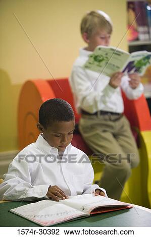 Stock Image - Schoolboy studying in the library. Fotosearch