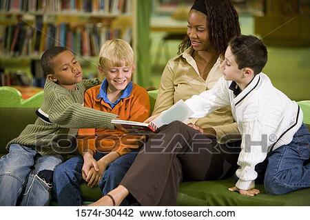 Stock Image - Schoolboys pointing at a book held by the teacher. Fotosearch