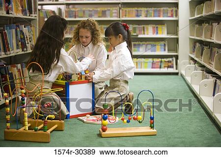 Schoolgirls arranging toys on floor in the library View Large Photo Image Stock Photo - Schoolgirls arranging toys on floor in the library. Fotosearch