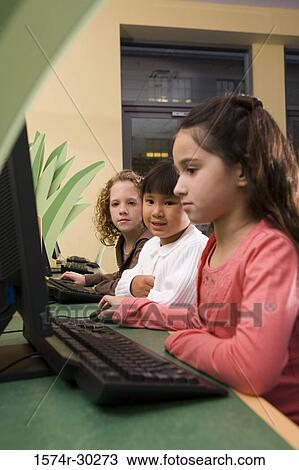 Stock Image - Schoolgirls using computer in the library. Fotosearch
