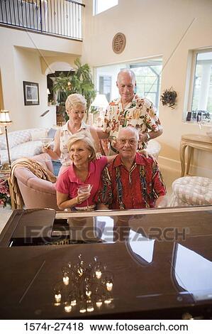 Stock Photo - Senior man playing piano while friends listening the music. Fotosearch