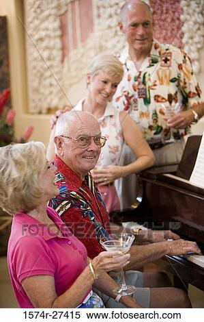 Stock Photography - Senior man playing piano while friends listening the music. Fotosearch