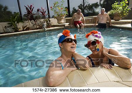 Senior women in swimming pool while senior men sitting on poolside View Large Photo Image Stock Photograph - Senior women in swimming pool while senior men sitting on poolside. Fotosearch