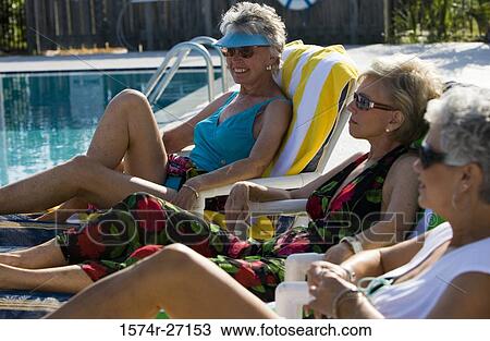 Senior women relaxing on reclining chair by swimming pool View Large Photo Image Stock Image - Senior women relaxing on reclining chair by swimming pool. Fotosearch