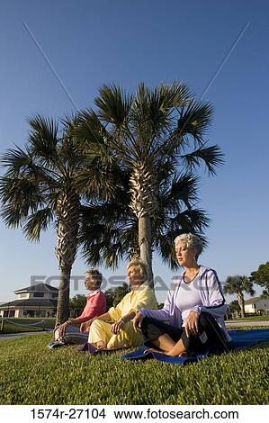 Picture - Senior women sitting on exercise mat and meditating. Fotosearch