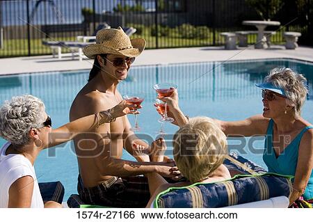 Shirtless young man by pool with senior women toasting drinks View Large Photo Image Stock Photograph - Shirtless young man by pool with senior women toasting drinks. Fotosearch