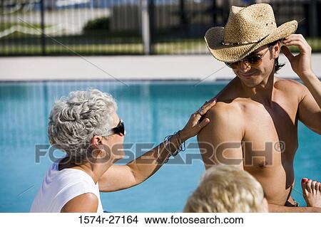 Shirtless young man sitting with senior women by pool View Large Photo Image Picture - Shirtless young man sitting with senior women by pool. Fotosearch