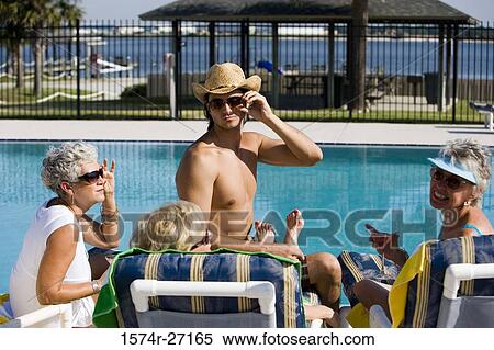 Shirtless young man sitting with senior women by pool View Large Photo Image Stock Photography - Shirtless young man sitting with senior women by pool. Fotosearch