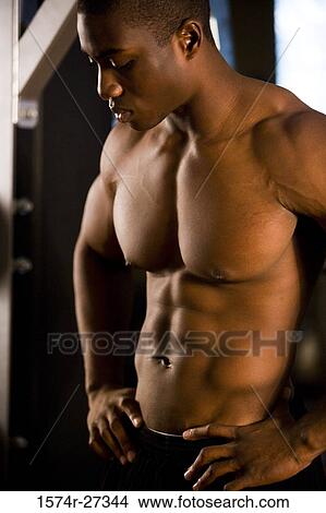 Shirtless young man standing in the gym and looking down View Large Photo Image Picture - Shirtless young man standing in the gym and looking down. Fotosearch