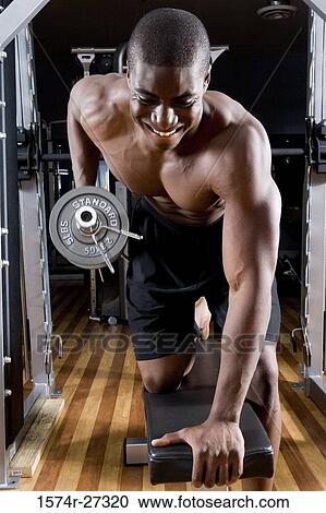 Shirtless young man working out with dumbbells in the gym View Large Photo Image Stock Image - Shirtless young man working out with dumbbells in the gym. Fotosearch