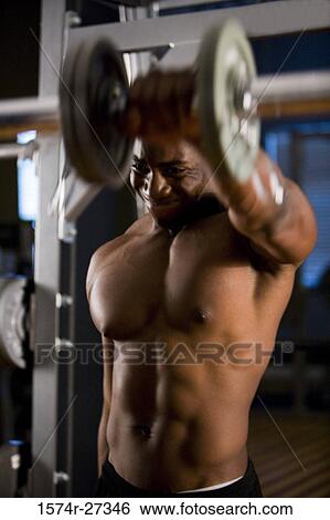 Shirtless young man working out with dumbbells in the gym View Large Photo Image Stock Photograph - Shirtless young man working out with dumbbells in the gym. Fotosearch